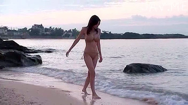 Joven asiático solitario con pechos grandes camina en la playa