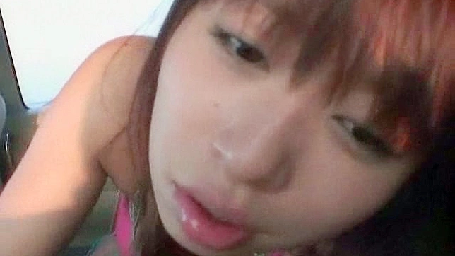 Chica asiática hambrienta y graciosa chupando en el coche